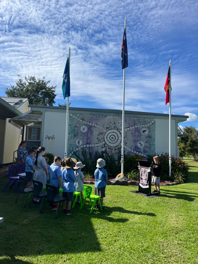 Anzac day Assembly. Children outside standing infront of the flags